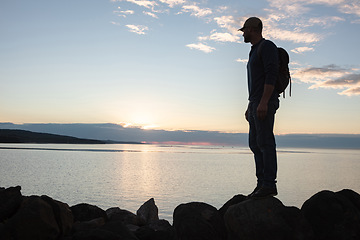 Image showing Hiking soothes and clears the head. a man wearing his backpack while out for a hike on a coastal trail.