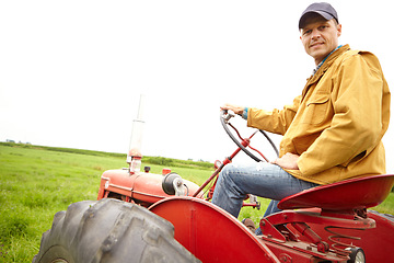 Image showing Preparing for a hard days work. A farmer sitting on his tractor and looking at the camera on an open field with copyspace.