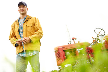 Image showing Admiring the view. A farmer standing in a field with his tractor parked behind him - Copyspace.