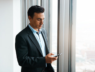 Image showing Looks like I have a meeting in an hour...a well-dressed businessman using his cellphone at the office.