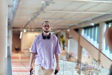 Image showing In a contemporary startup office, a modern blond entrepreneur stands, engrossed in his smartphone, epitomizing the dynamic and tech-savvy essence of the modern business world.