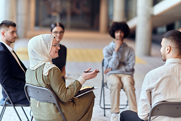 Image showing A diverse group of young business entrepreneurs gathered in a circle for a meeting, discussing corporate challenges and innovative solutions within the modern confines of a large corporation