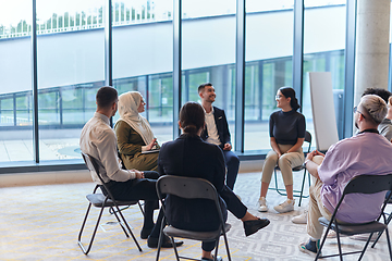 Image showing A diverse group of young business entrepreneurs gathered in a circle for a meeting, discussing corporate challenges and innovative solutions within the modern confines of a large corporation