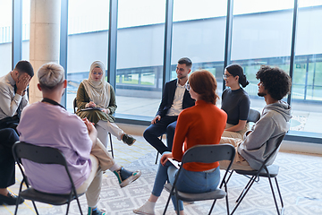 Image showing A diverse group of young business entrepreneurs gathered in a circle for a meeting, discussing corporate challenges and innovative solutions within the modern confines of a large corporation