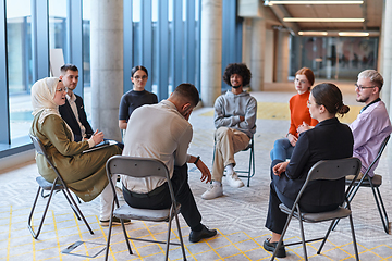 Image showing A diverse group of young business entrepreneurs gathered in a circle for a meeting, discussing corporate challenges and innovative solutions within the modern confines of a large corporation