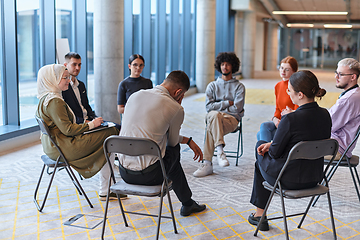 Image showing A diverse group of young business entrepreneurs gathered in a circle for a meeting, discussing corporate challenges and innovative solutions within the modern confines of a large corporation