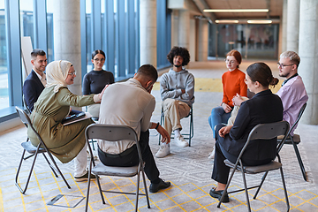 Image showing A diverse group of young business entrepreneurs gathered in a circle for a meeting, discussing corporate challenges and innovative solutions within the modern confines of a large corporation