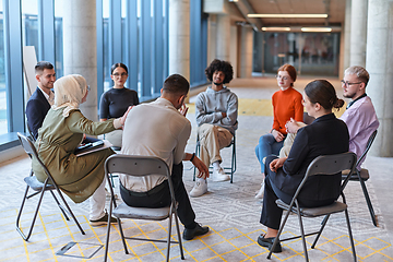 Image showing A diverse group of young business entrepreneurs gathered in a circle for a meeting, discussing corporate challenges and innovative solutions within the modern confines of a large corporation