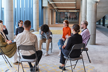 Image showing A diverse group of young business entrepreneurs gathered in a circle for a meeting, discussing corporate challenges and innovative solutions within the modern confines of a large corporation