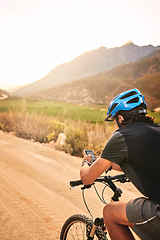 Image showing Which way will this trail take me...a young man using his cellphone while cycling along a trail.