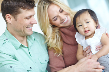 Image showing Parenthood is so fulfilling. A happy couple spending time with their beautiful adopted daughter while at home.