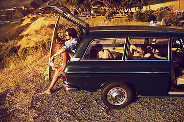 Image showing Go see whats out there. a young couple relaxing by their car during a roadtrip.