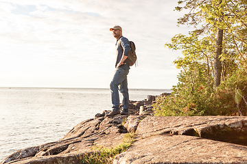 Image showing With each new excursion you will discover beautiful landscapes. a man wearing his backpack while out for a hike on a coastal trail.