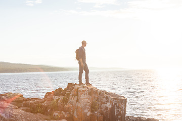 Image showing The climb is guaranteed to make you sweat. a man wearing his backpack while out for a hike on a coastal trail.