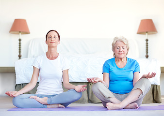 Image showing Rejuvenating the spirit. Senior woman sits in the lotus position while doing yoga with her trainer.