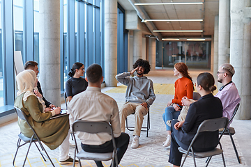 Image showing A diverse group of young business entrepreneurs gathered in a circle for a meeting, discussing corporate challenges and innovative solutions within the modern confines of a large corporation