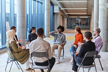 Image showing A diverse group of young business entrepreneurs gathered in a circle for a meeting, discussing corporate challenges and innovative solutions within the modern confines of a large corporation