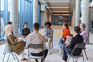 Image showing A diverse group of young business entrepreneurs gathered in a circle for a meeting, discussing corporate challenges and innovative solutions within the modern confines of a large corporation