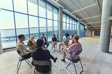 Image showing A diverse group of young business entrepreneurs gathered in a circle for a meeting, discussing corporate challenges and innovative solutions within the modern confines of a large corporation