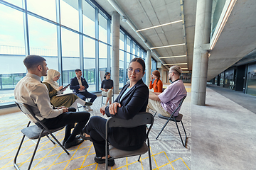 Image showing A diverse group of young business entrepreneurs gathered in a circle for a meeting, discussing corporate challenges and innovative solutions within the modern confines of a large corporation