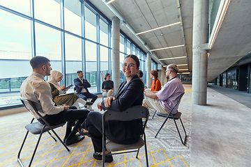 Image showing A diverse group of young business entrepreneurs gathered in a circle for a meeting, discussing corporate challenges and innovative solutions within the modern confines of a large corporation