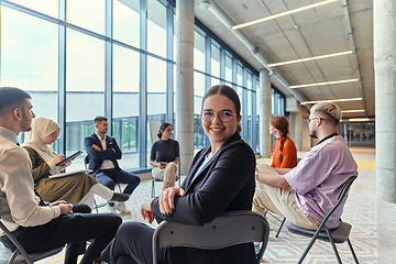 Image showing A diverse group of young business entrepreneurs gathered in a circle for a meeting, discussing corporate challenges and innovative solutions within the modern confines of a large corporation