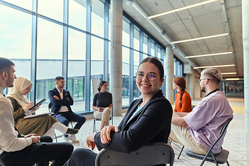 Image showing A diverse group of young business entrepreneurs gathered in a circle for a meeting, discussing corporate challenges and innovative solutions within the modern confines of a large corporation