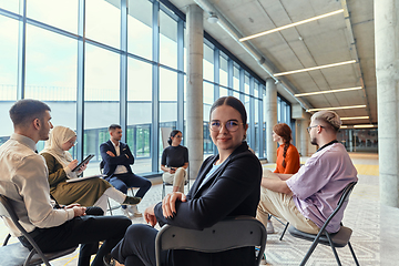 Image showing A diverse group of young business entrepreneurs gathered in a circle for a meeting, discussing corporate challenges and innovative solutions within the modern confines of a large corporation