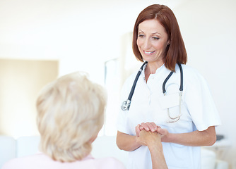 Image showing Her presence is a part of their recovery. Friendly mature nurse comforts her elderly patient by holding her hand affectionately.