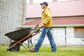 Image showing Cleaning up the garden. A man walking outside with his wheelbarrow.