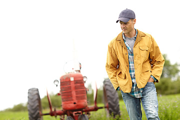 Image showing Getting lost in a moment. a farmer walking with his tractor behind him in a field.