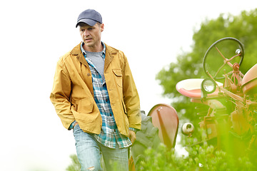 Image showing Deep in thought. a worried farmer walking away from his tractor in a field.