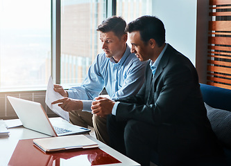 Image showing Lets just go over it together. two businessmen having a discussion while sitting by a laptop.