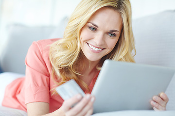 Image showing Doing all her shopping via the web. a beautiful young woman using her digital tablet and credit card to shop online.