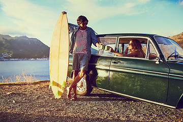 Image showing Heres to the open road. a young couple relaxing by their car during a roadtrip.