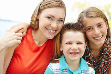 Image showing She is proud of her children. Smiling mother embracing her teen daughter and young son while outdoors.