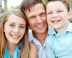 Image showing Dad and his little ones. Handsome father embracing his teen daughter and young son while outdoors.