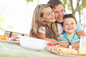 Image showing Big hug from dad. Father hugging his daughter and son at the picnic table.