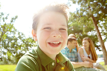 Image showing He always has fun with his family. A happy little boy sitting outdoors with his family on a sunny day.