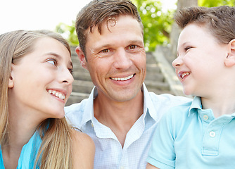 Image showing We love our dad. Handsome father embracing his teen daughter and young son while outdoors.