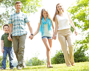 Image showing Summer strolls as a family. A happy young family walking through the park together on a summers day.