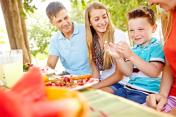 Image showing Lets eat. A happy young family relaxing in the park and enjoying a healthy picnic.