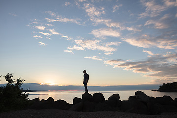 Image showing This hike was so worth it. a man wearing his backpack while out for a hike on a coastal trail.