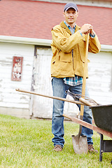 Image showing Almost time to start digging. Portrait of a happy man standing next to a wheelbarrow with a spade in his hand.