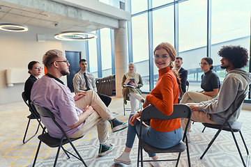 Image showing A diverse group of young business entrepreneurs gathered in a circle for a meeting, discussing corporate challenges and innovative solutions within the modern confines of a large corporation