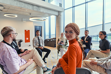 Image showing A diverse group of young business entrepreneurs gathered in a circle for a meeting, discussing corporate challenges and innovative solutions within the modern confines of a large corporation