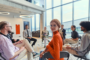 Image showing A diverse group of young business entrepreneurs gathered in a circle for a meeting, discussing corporate challenges and innovative solutions within the modern confines of a large corporation