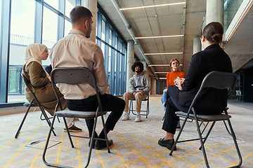 Image showing A diverse group of young business entrepreneurs gathered in a circle for a meeting, discussing corporate challenges and innovative solutions within the modern confines of a large corporation