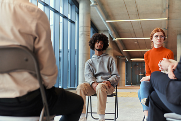 Image showing A diverse group of young business entrepreneurs gathered in a circle for a meeting, discussing corporate challenges and innovative solutions within the modern confines of a large corporation