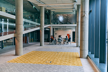 Image showing A diverse group of young business entrepreneurs gathered in a circle for a meeting, discussing corporate challenges and innovative solutions within the modern confines of a large corporation